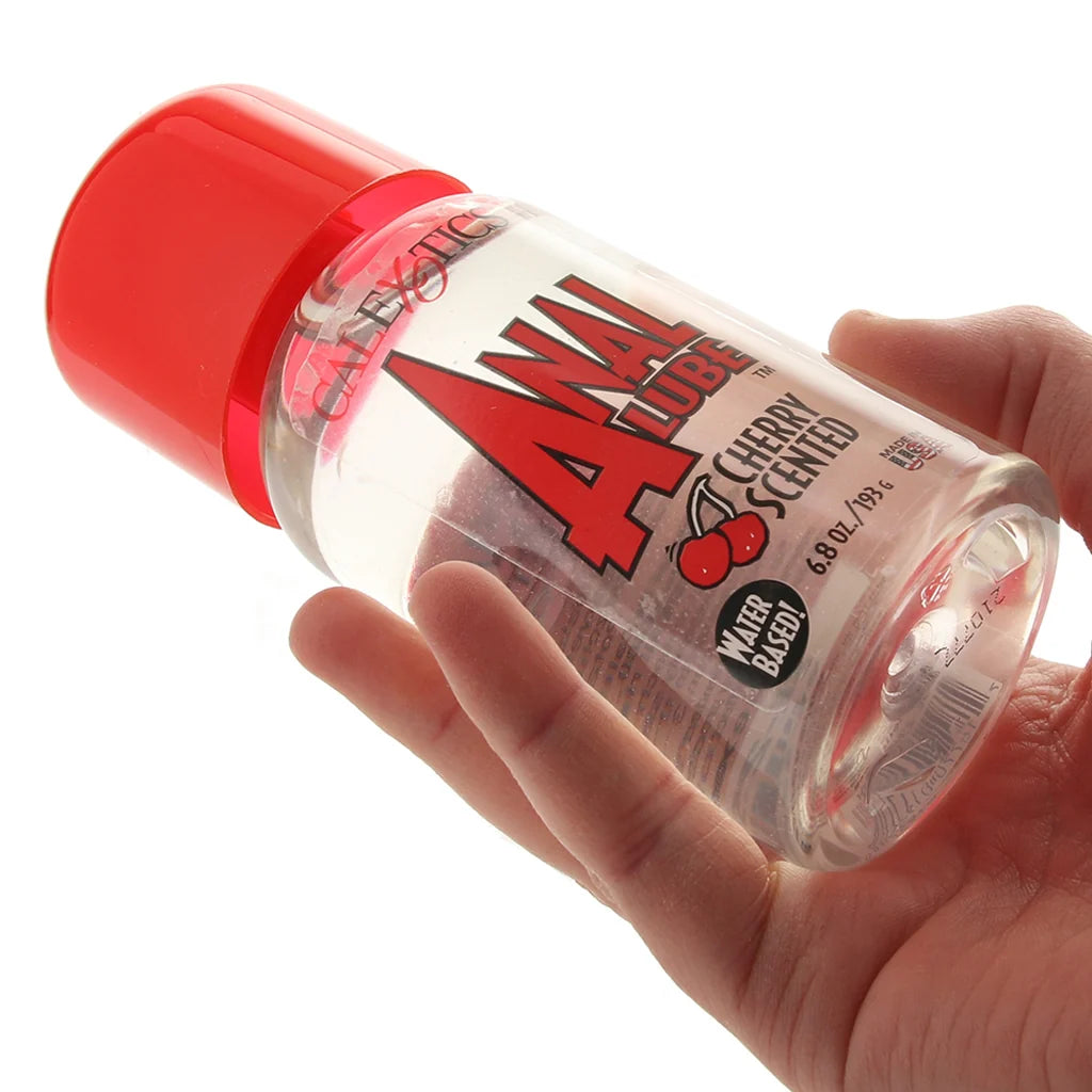 Hand holding a bottle of Anal Lube with a red cap on a white background